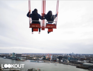 A swing over the edge of a tall building with city views of Amsterdam