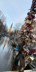 A bridge full of padlocks with a canal in the background