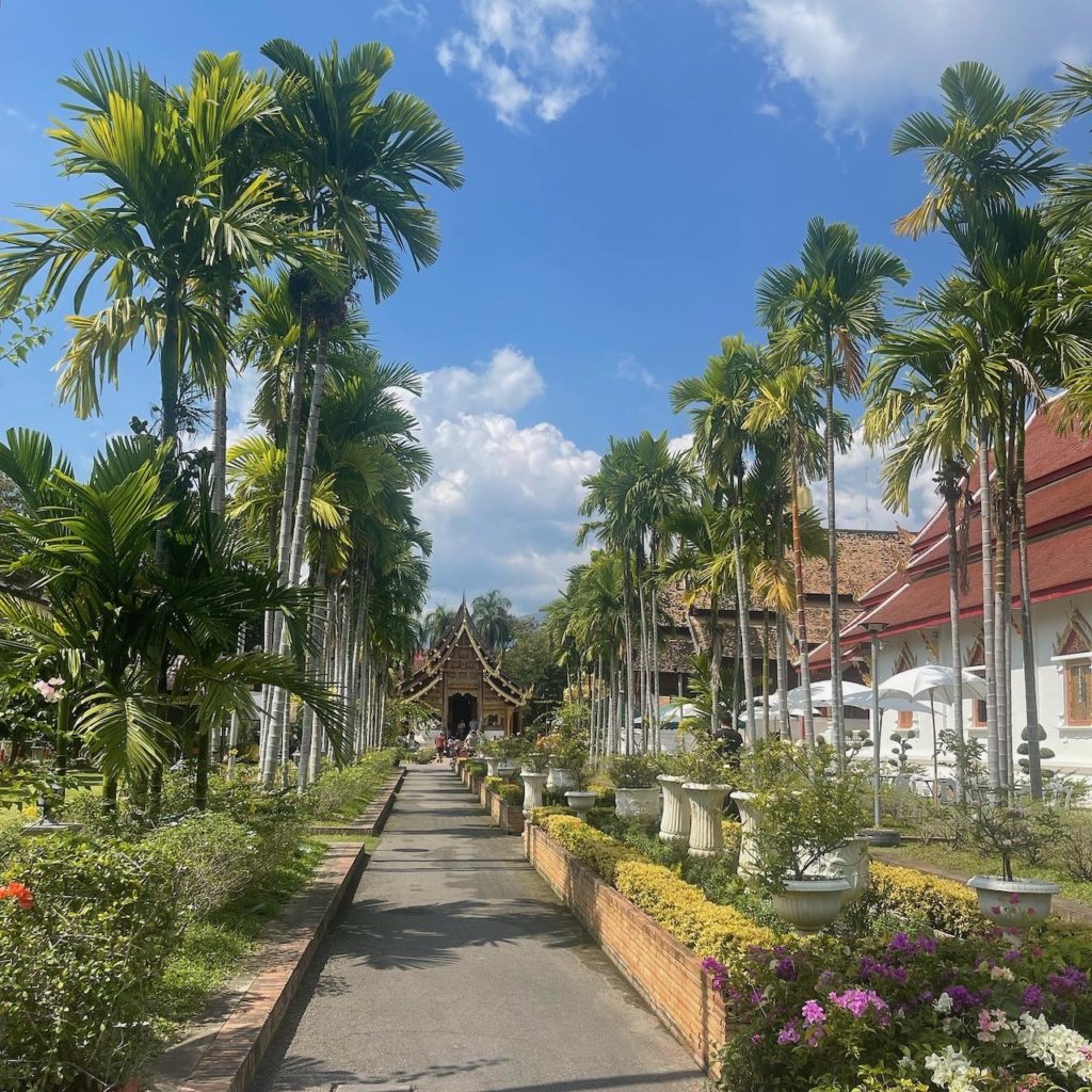 The grounds of a beautiful temple, surrounded by palm trees and a well kept garden.