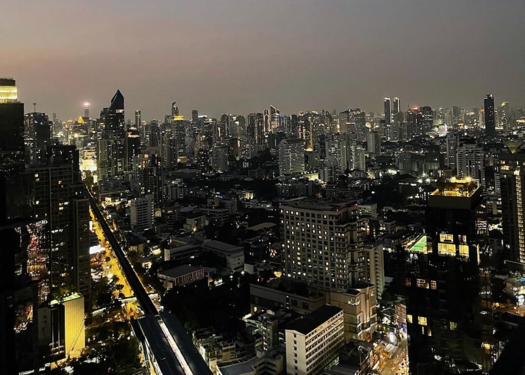 An immense city at dusk with dozens of skyscrapers towering the skyline.