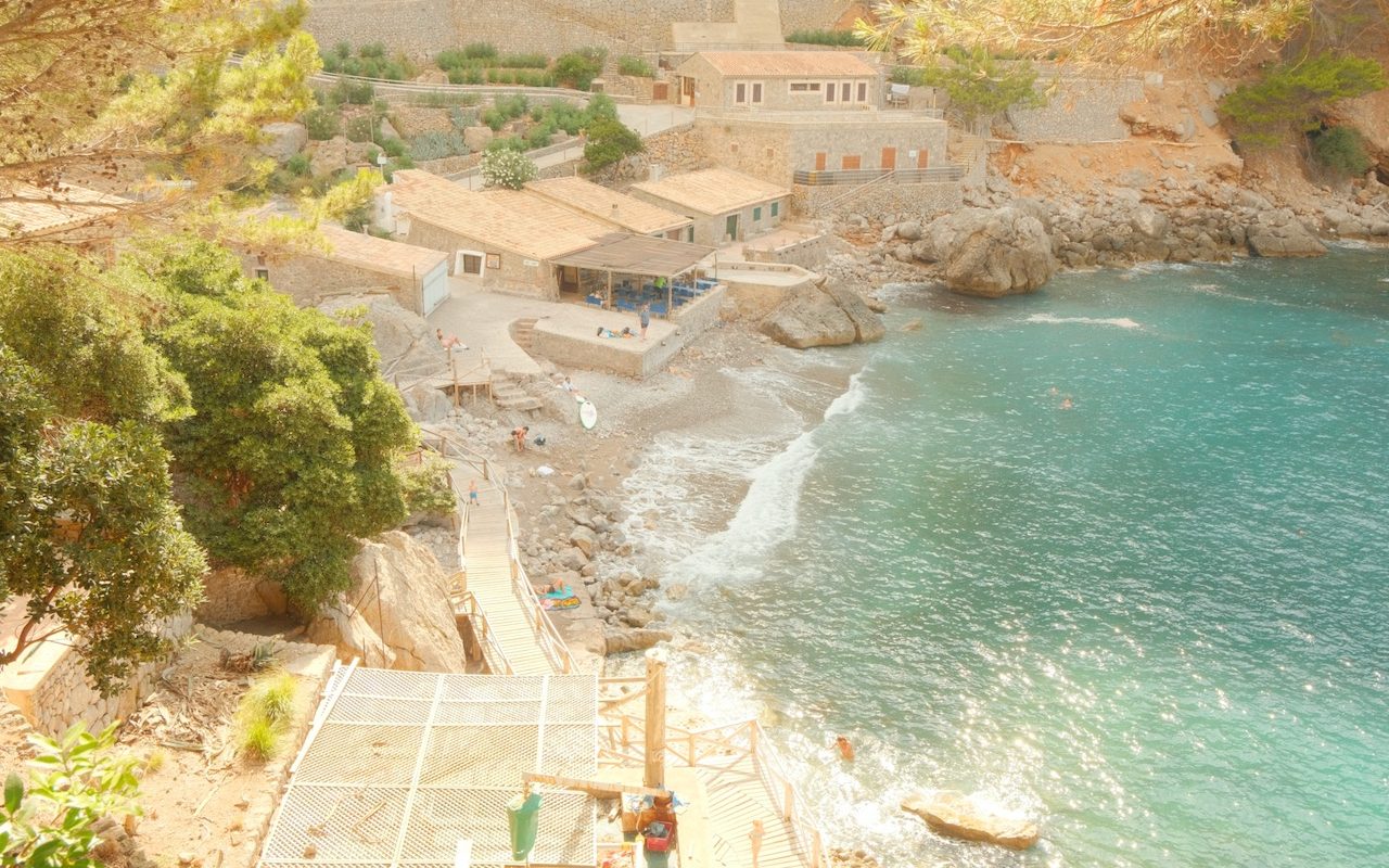 A hidden gem in Mallorca, a serene beach with typical Spanish building surrounding it.
