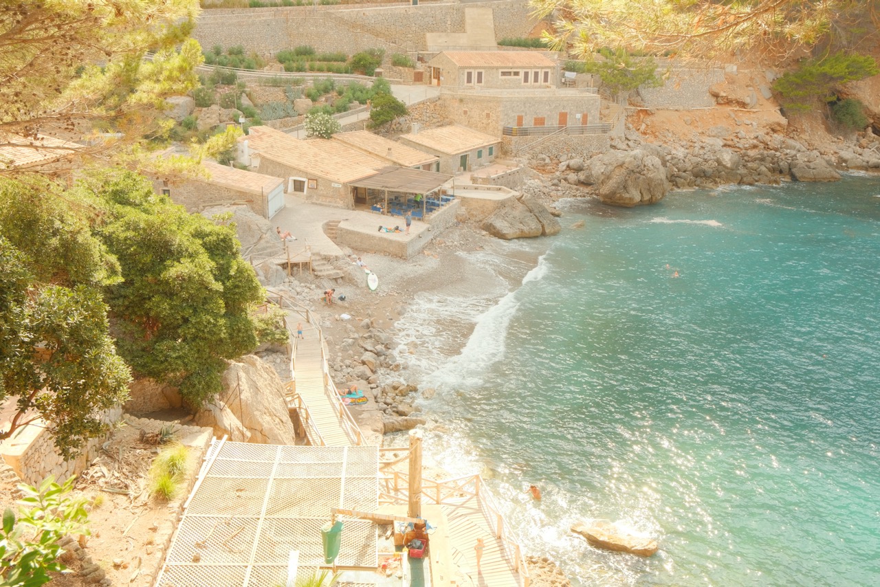 A hidden gem in Mallorca, a serene beach with typical Spanish building surrounding it.