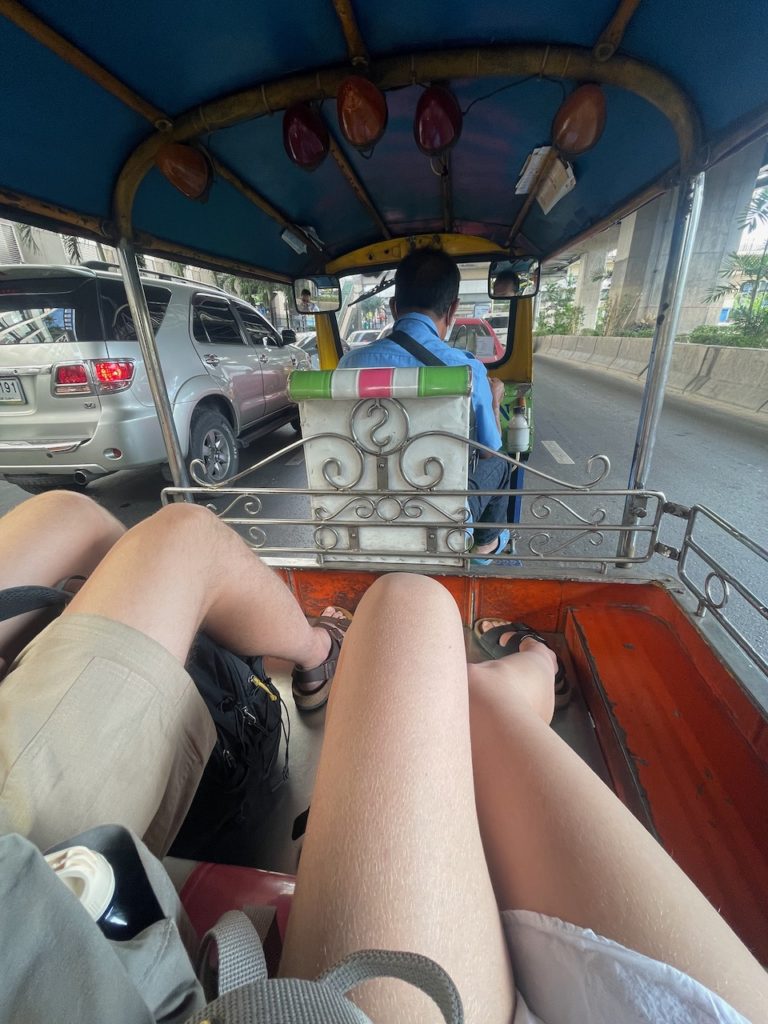 Tourists sat in the back of a tuk tuk in Bangkok.