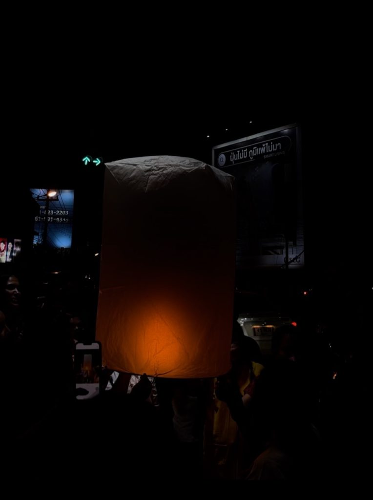 A lantern about to be released into the sky, glowing orange.