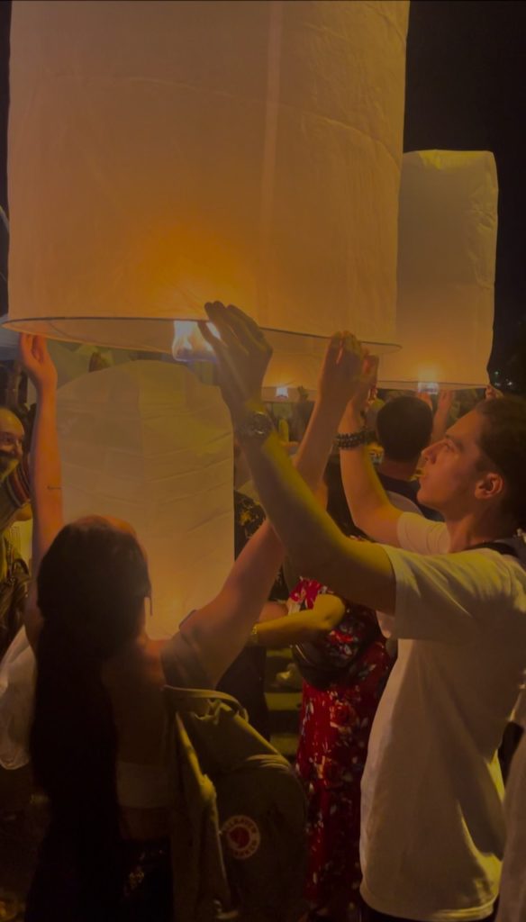 A couple releasing a rice paper lantern into the sky to celebrate Yi Peng.