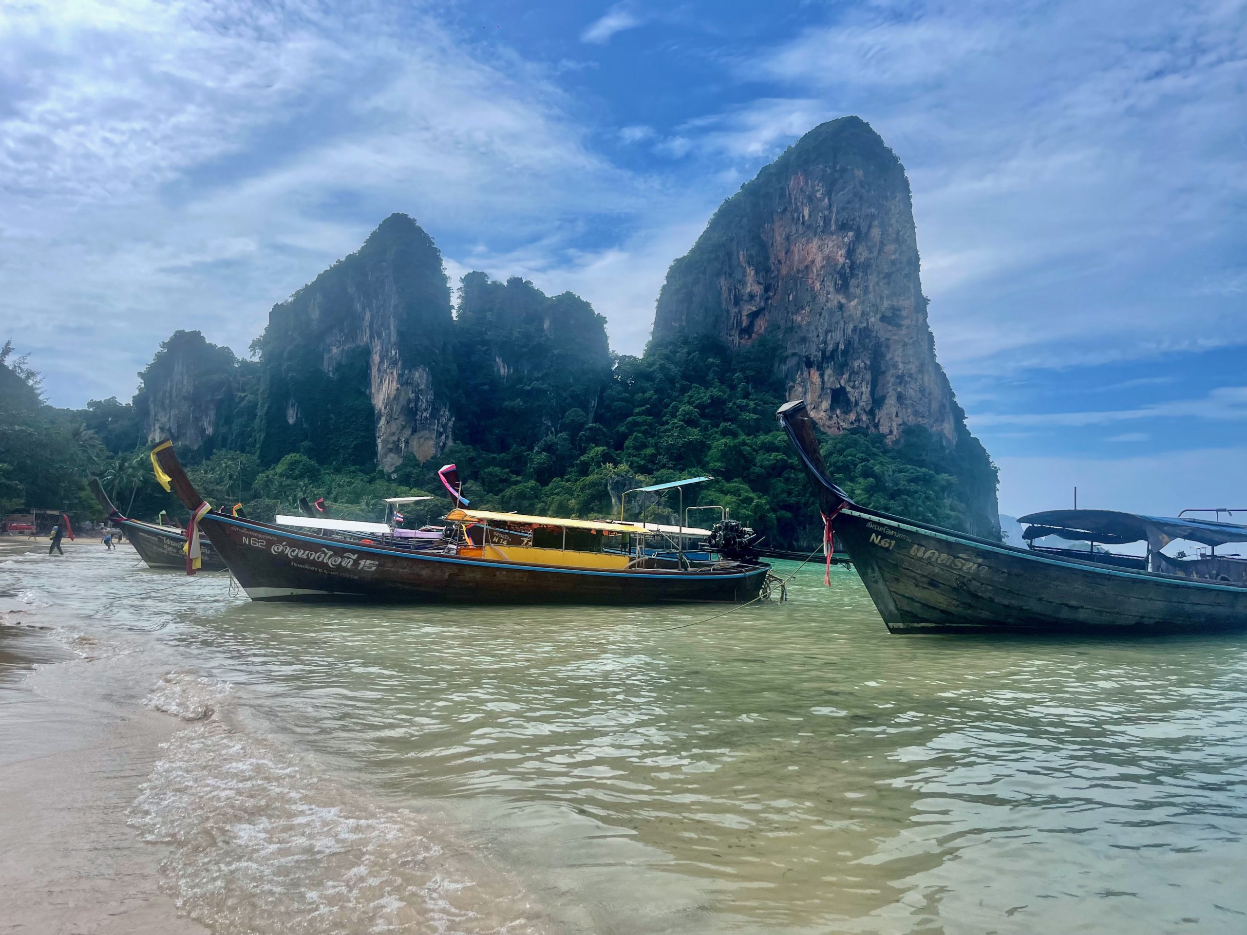 Longtail boats on Krabi's famous Railay Beach with limestone cliffs in the background
