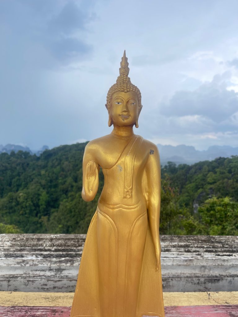 A statue of a Buddha on top of a mountain in Krabi