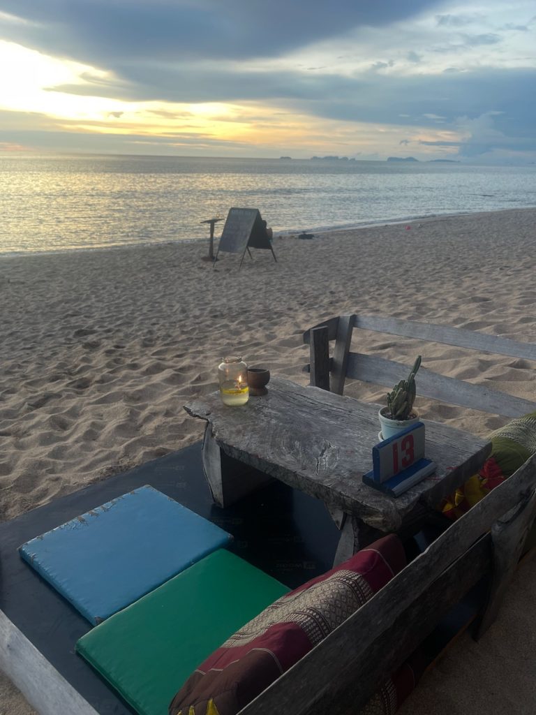 A serene beach scene with a wooden bench, inviting visitors to relax and enjoy the view with a cocktail of choice.