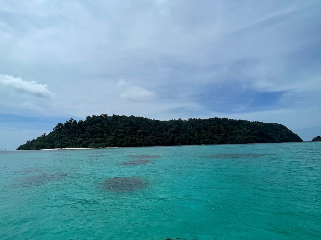 A solitary island, known as Bamboo Island, amidst vast oceanic expanse, offering a serene and secluded refuge.