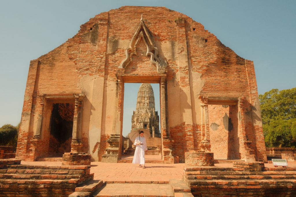 A woman posing with an umbrella in front of an ancient temple complex.