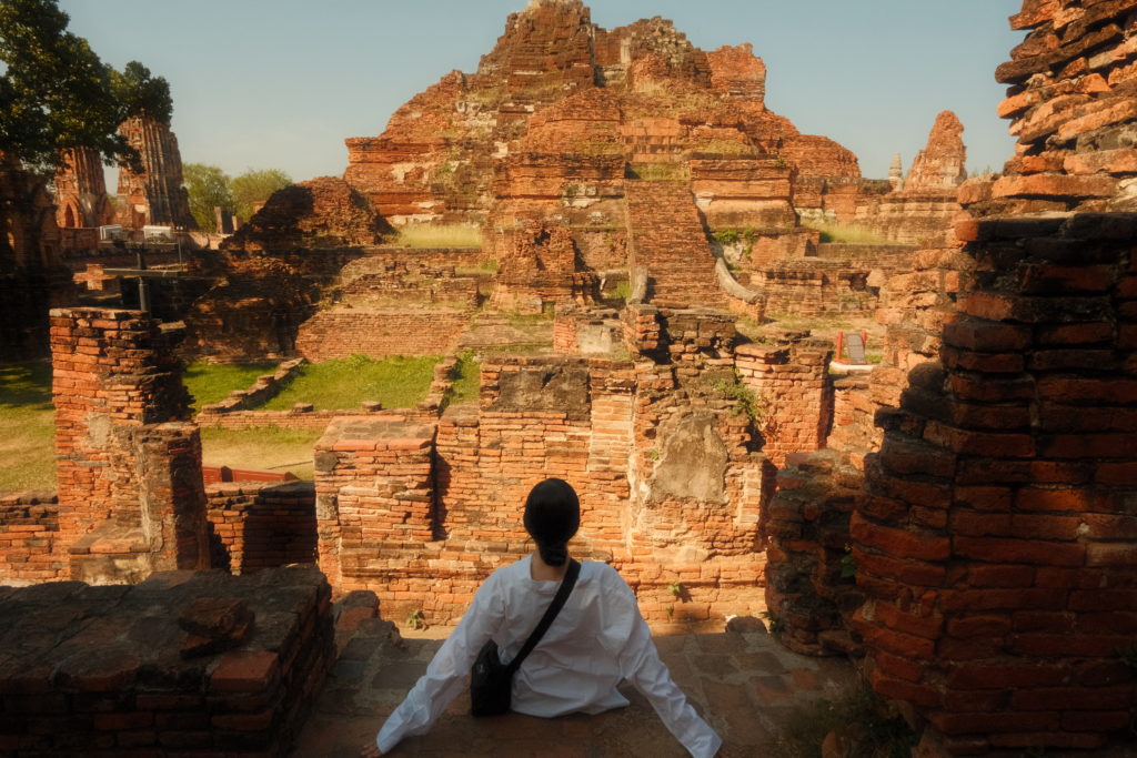 A woman sat admiring the views of a huge ancient temple complex.
