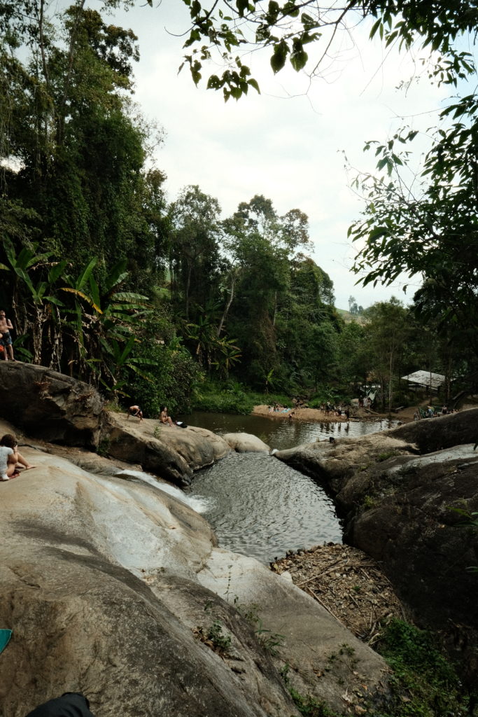 A waterfall with multiple pools, ideal for swimming, surrounded by jungle vegetation.