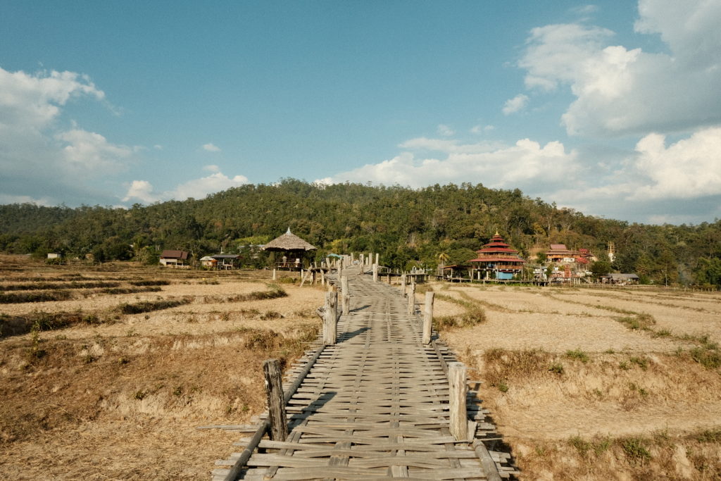 A locally made bamboo bridge within the rice fields of Pai, surrounded by nature.