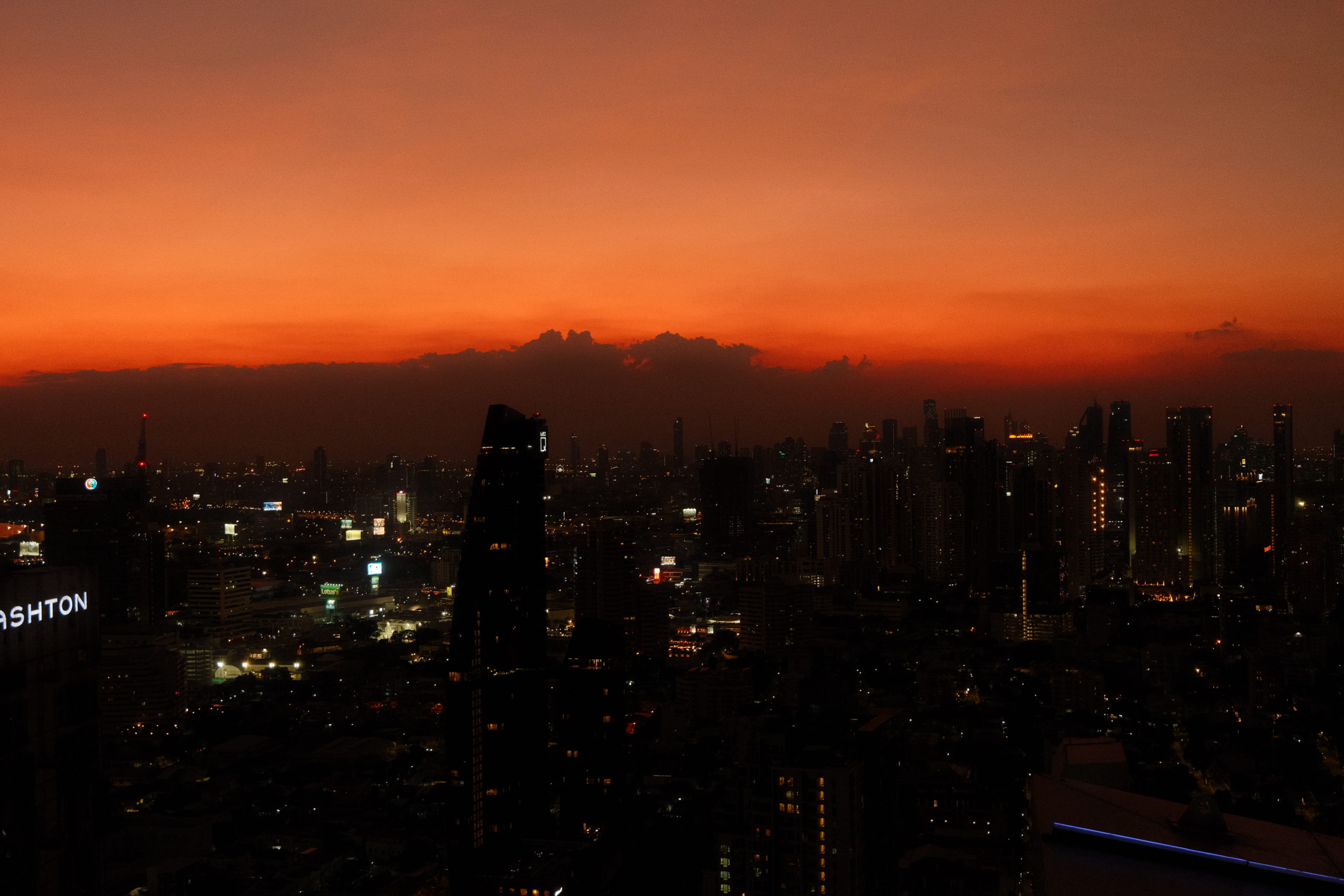An intense orange and purple sunset over the many skyscrapers of Bangkok.