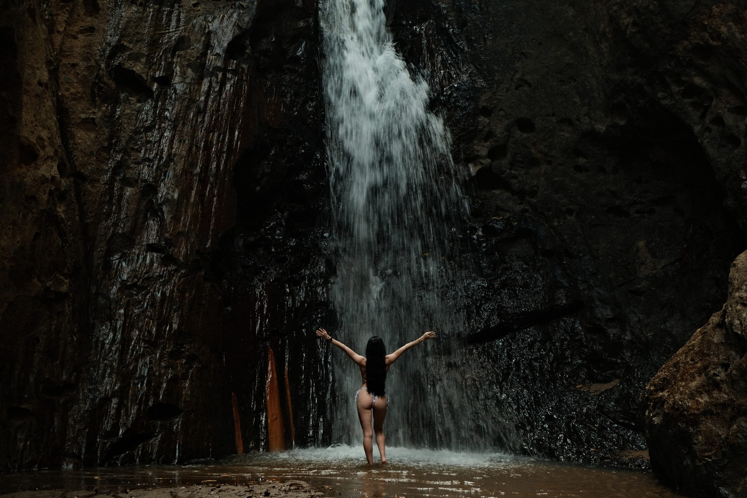A woman standing in amazement at a beautiful huge waterfall.