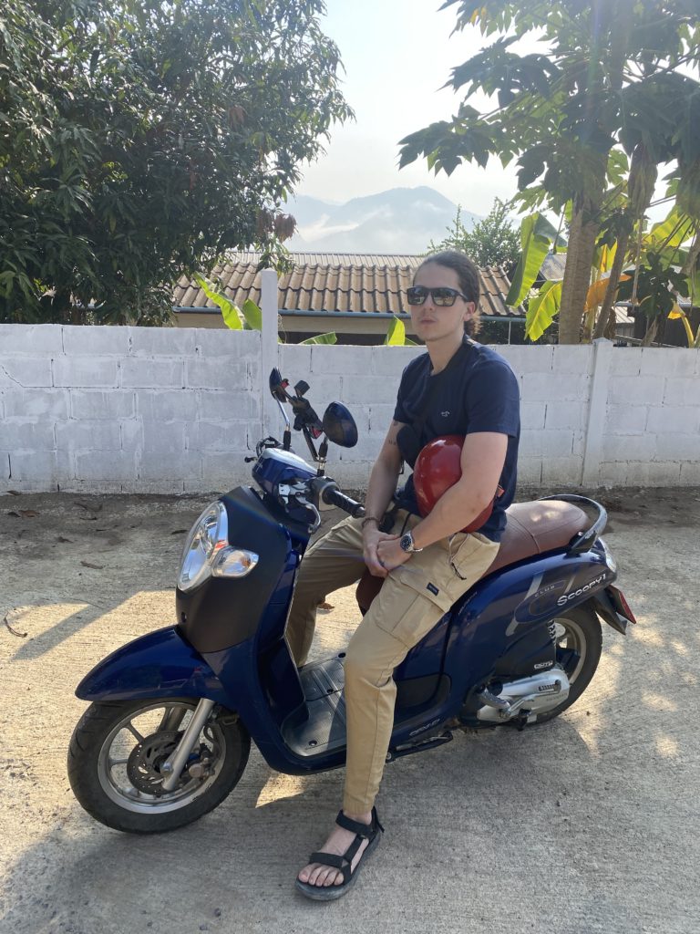 A man seated on a motorcycle with a stunning view of a mountain in the background.