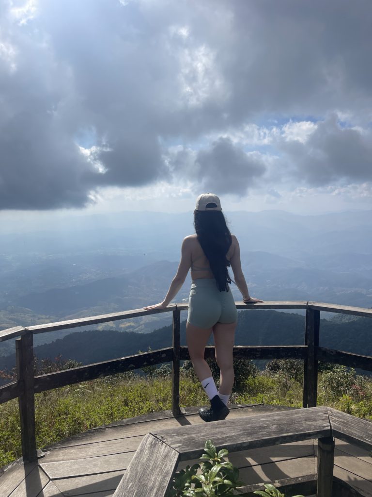 A woman mid hike at a view point overlooking the tallest point in Thailand.