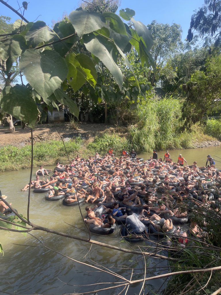 Lots of tourists gathered in rubber rings in the middle of a river in Thailand.