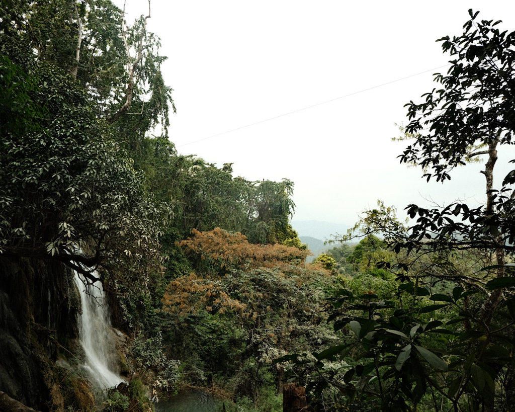 A view from above Kuang Si Waterfall surrounded by lush green vegetation in the jungle.