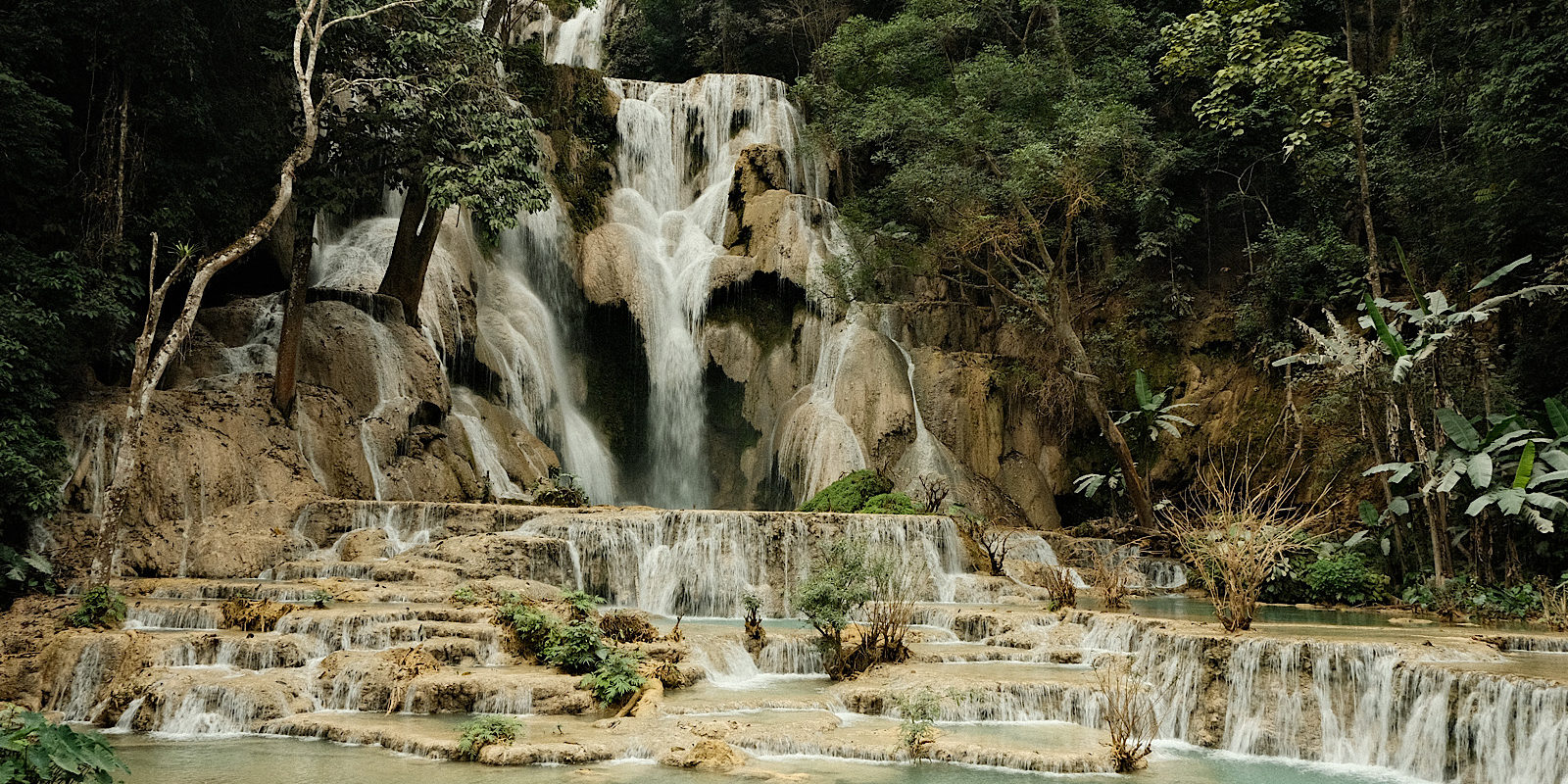 Kuang Si Waterfall in Laos, a picturesque natural wonder surrounded by lush greenery and cascading waters.