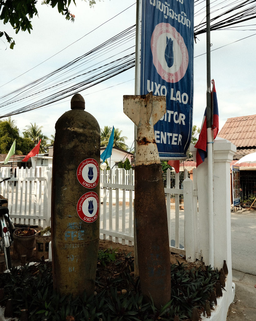 Bombs situated in front of a white fence at a museum.