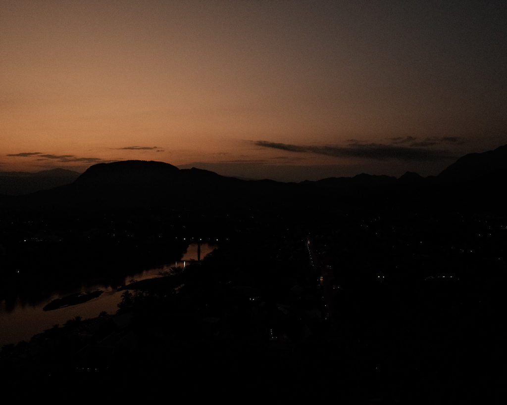 Pastel colours engulf the sky over Luang Prabang, viewed from the top of a mountain.