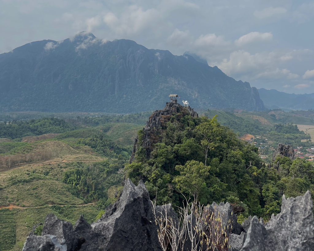A pegasus statue located on top of a limestone cliff with impressive mountains in the background.