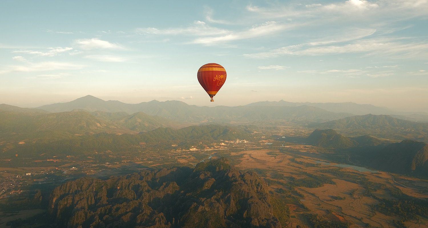 A hot air balloon soaring above majestic mountain peaks.