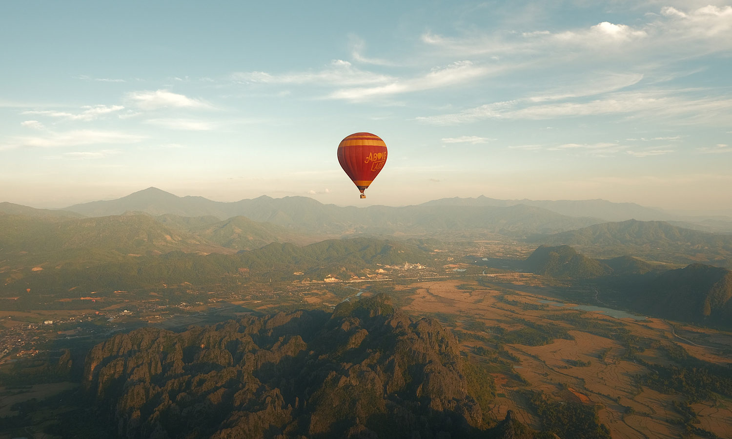 A hot air balloon soaring above majestic mountain peaks.