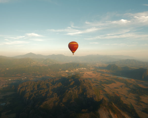 A hot air balloon soaring above majestic mountain peaks.