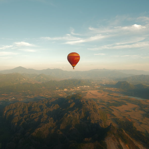 A hot air balloon soaring above majestic mountain peaks.