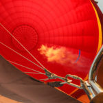 A flame inside of a red hot air balloon.