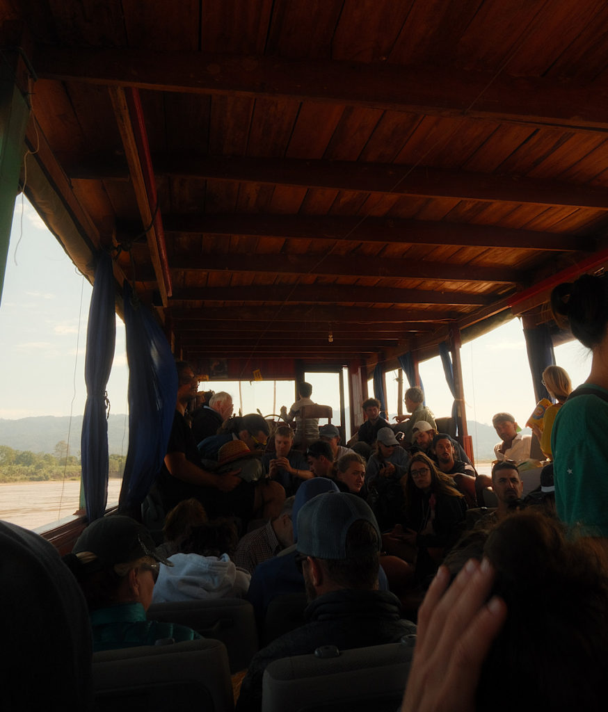 An overcrowded wooden slow boat, packed with travellers.