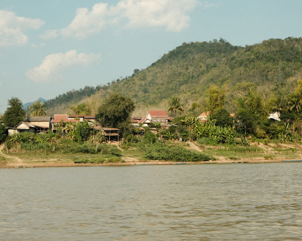 Rural scenery on the riverfront with mountainous terrain in the background.