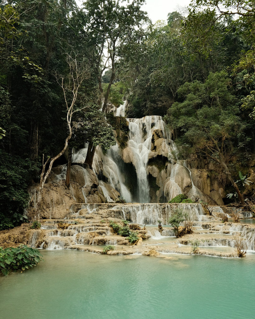 A majestic waterfall cascading down a rocky cliff, surrounded by lush greenery and misty spray.