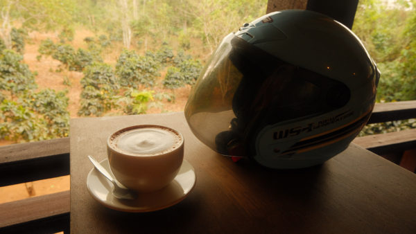 A bike helmet and a cup of coffee placed on a table, ready for a quick pick me up.