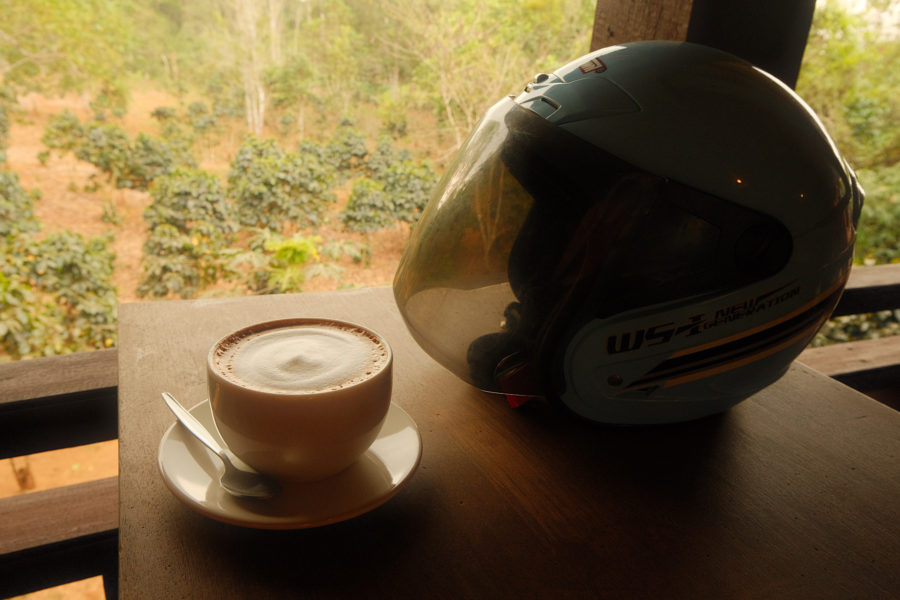 A bike helmet and a cup of coffee placed on a table, ready for a quick pick me up.