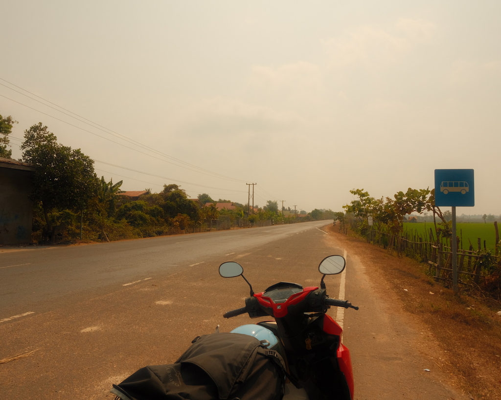 A red motorcycle parked on the side of a countryside road.