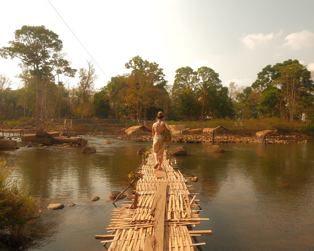 A woman crossing a bamboo bridge.