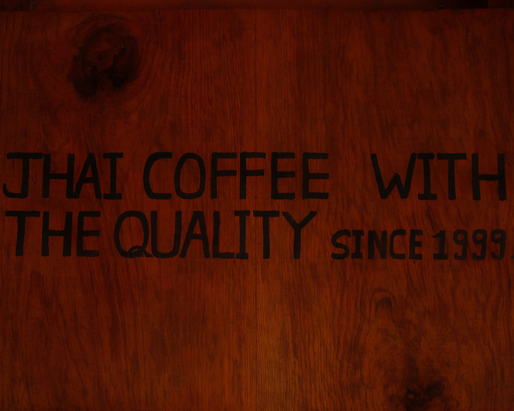 A dark wooden board displaying the name of a coffee shop.