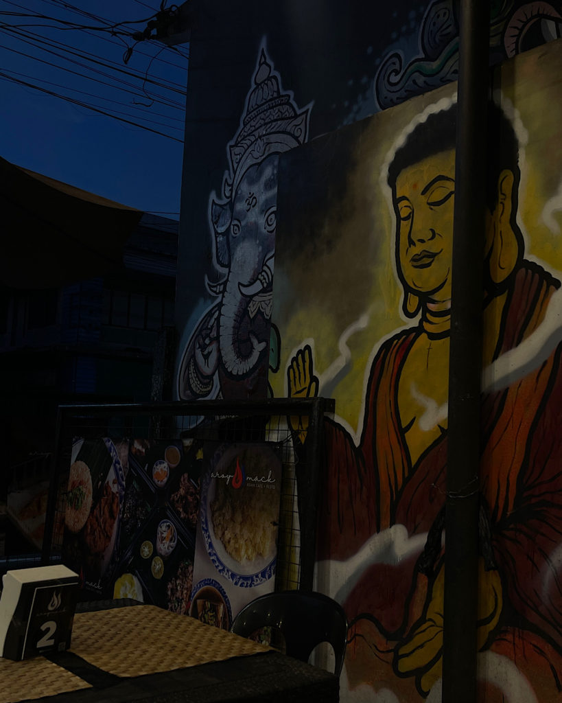 A restaurant with paintings of a Buddha.