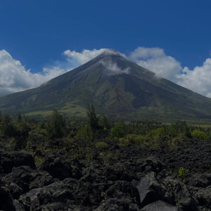 A perfect cone shaped volcano surrounded by black lava.