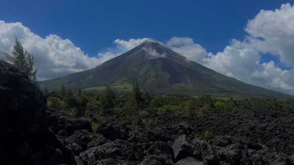A perfect cone shaped volcano surrounded by black lava.