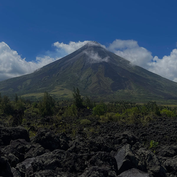 A perfect cone shaped volcano surrounded by black lava.