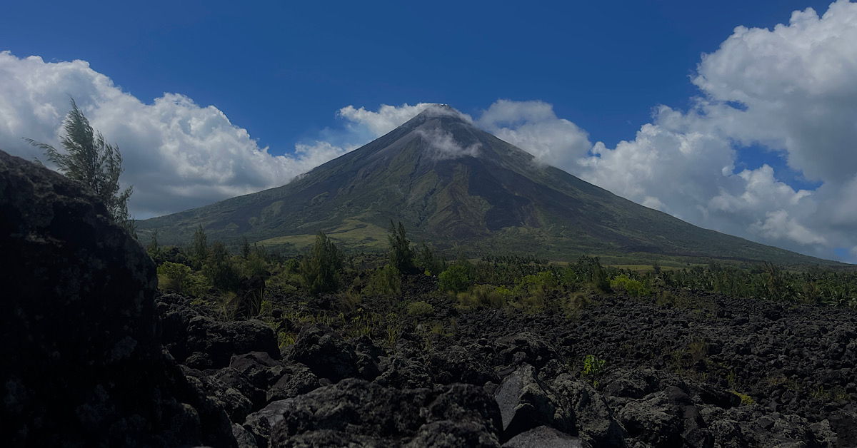 A perfect cone shaped volcano surrounded by black lava.