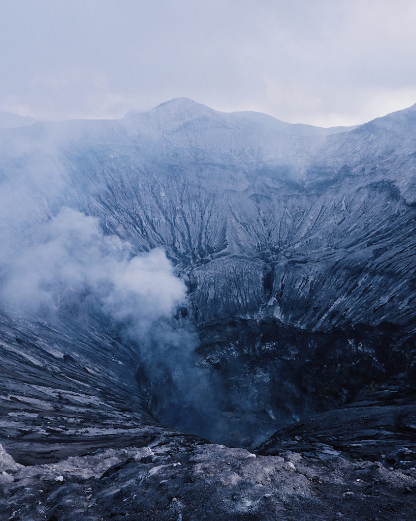 Aerial view of Bromo crater volcano emitting smoke.