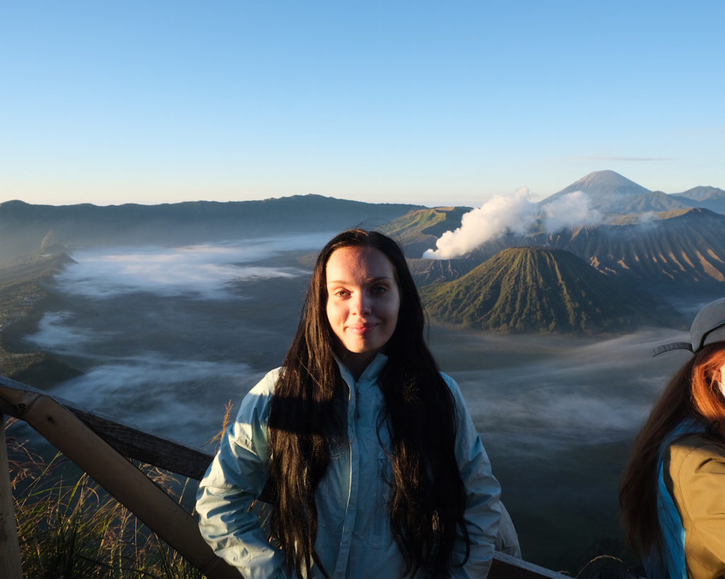 A woman in a blue raincoat standing infront of Mount Bromo.