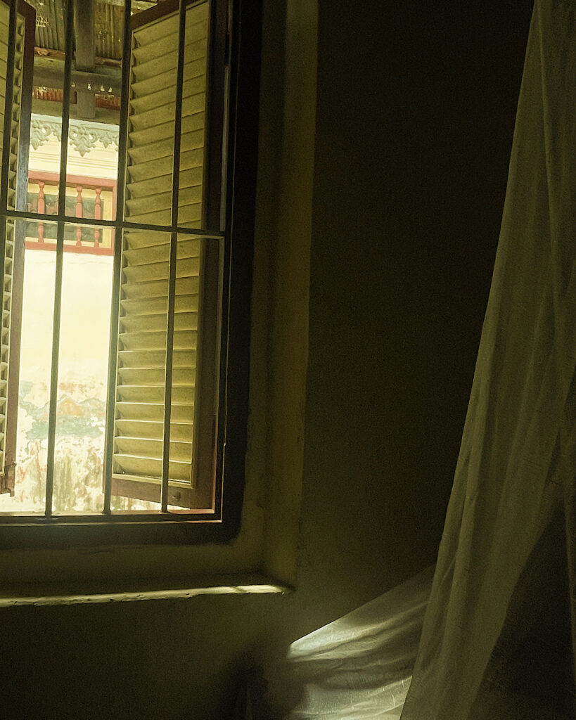 An open window with rustic shutters in an Indonesian homestay.