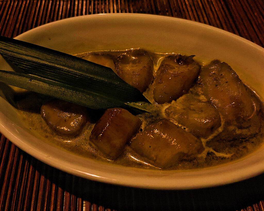 A bowl of boiled bananas in coconut milk with spices.