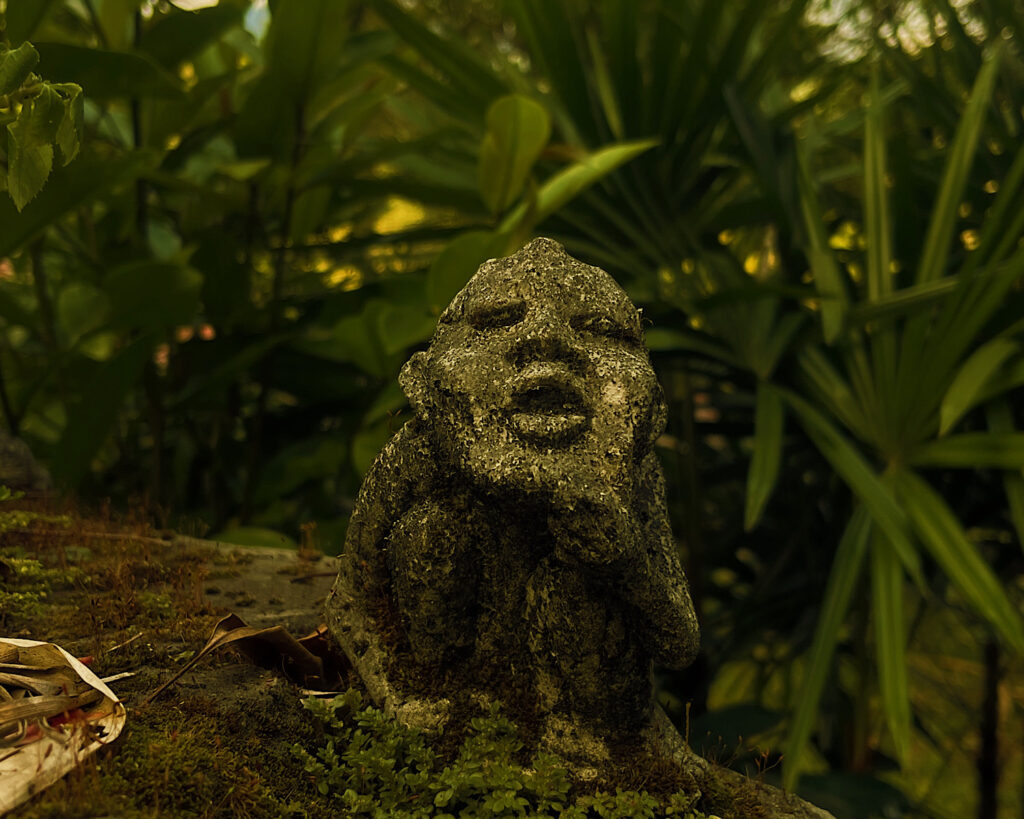 A small stone statue surrounded by greenery.